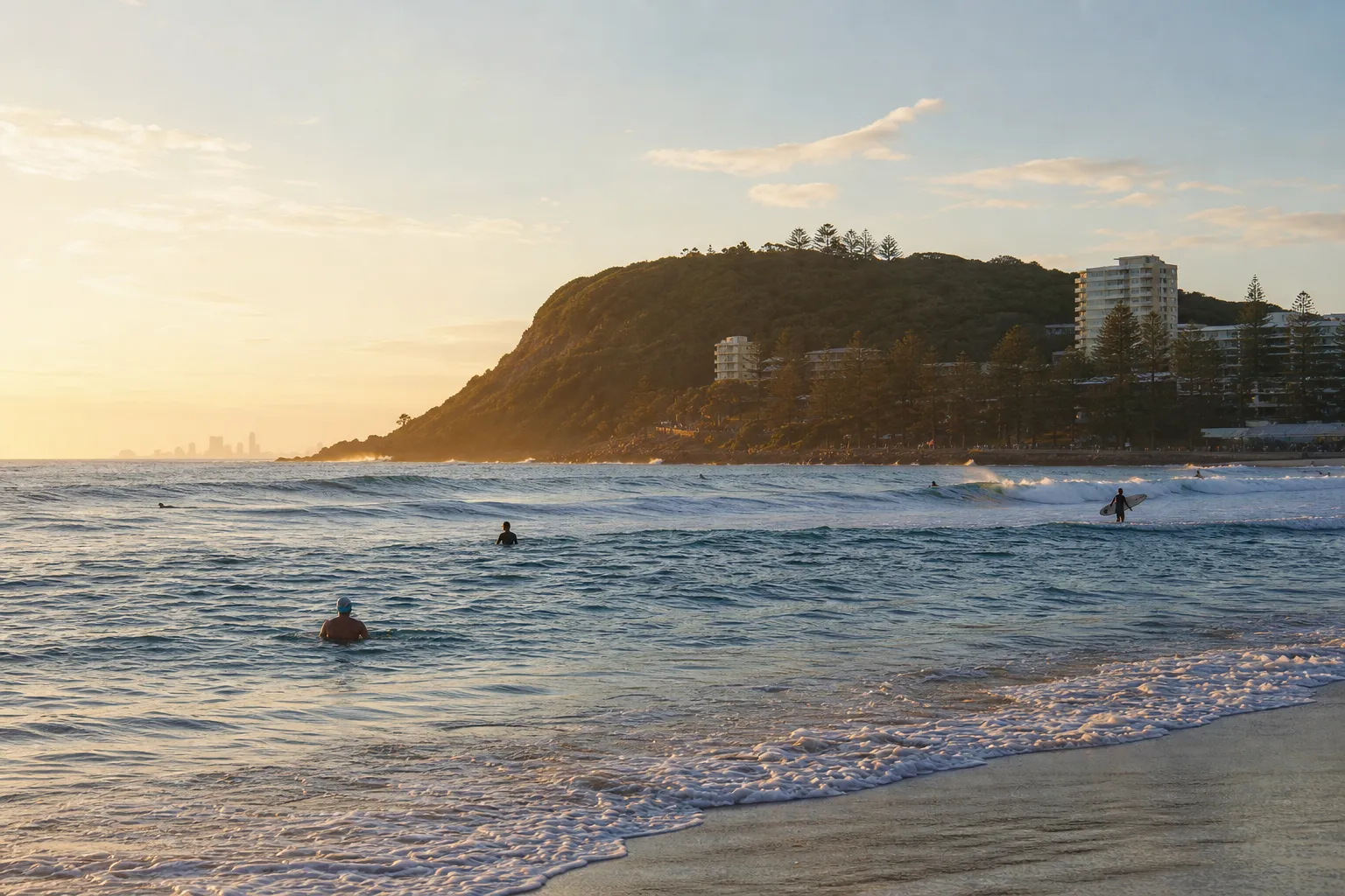 Early swimmers and surfers below Burleigh Headland at sunrise