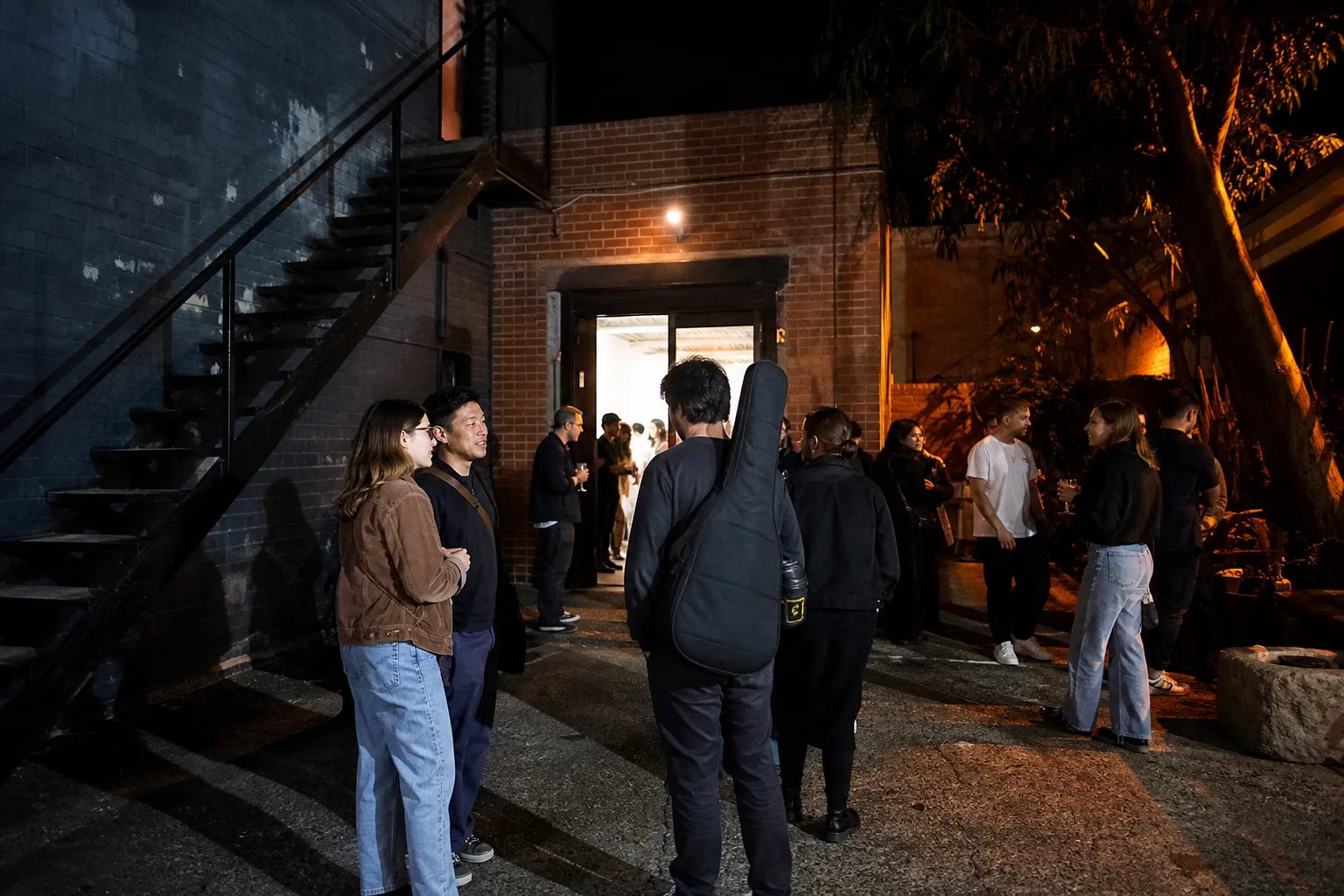 People talking after a live show in a warehouse courtyard
